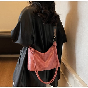 Sac bandoulière rose vintage avec large bandoulière brodée ethnique porté par un mannequin