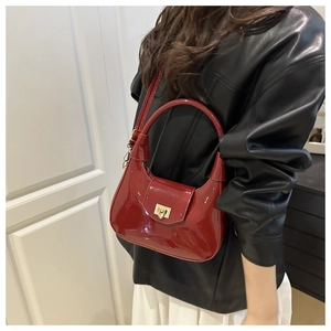 Detail of burgundy patent leather crescent bag with golden square metal rotating buckle
