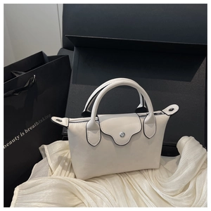 Detail of a cream leather mini tote featuring a round handle and silver metal buckle