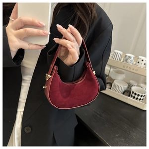 Detail of burgundy crescent bag featuring leather and suede patchwork with gold hardware