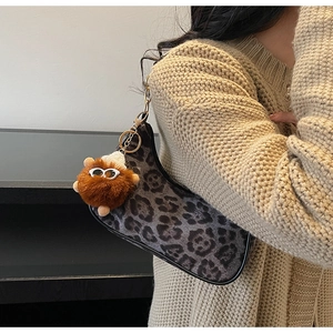 Detail of leopard print crescent bag with gold chain and plush monster charm