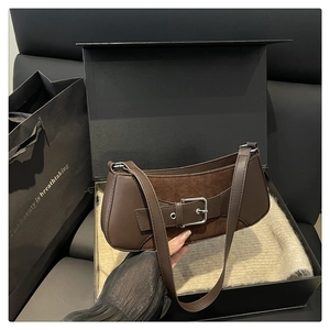 Detail of brown underarm bag showing faux leather and suede patchwork with silver buckle