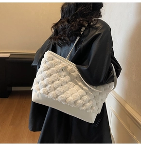 Vue détaillée du sac cabas blanc en fausse fourrure et cuir porté sur un manteau noir