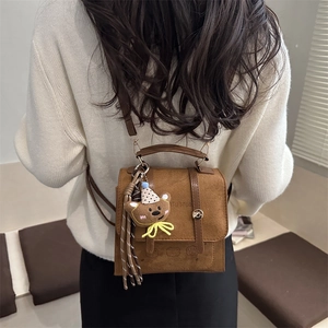 Minimalist brown suede backpack with cartoon bear pendant and studio logo embroidery