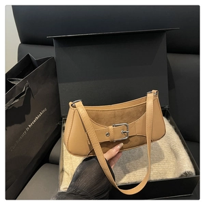 Detail of camel leather and suede underarm bag featuring silver buckle on a gift box