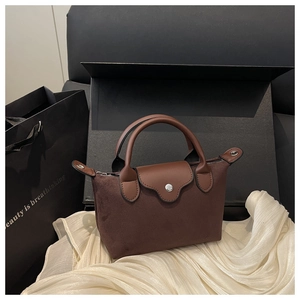 Macro detail of dark brown suede and leather stitching on the mini tote bag