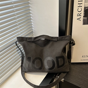 Borsa tote minimalista in tela nera con scritta MOOD mostrata in un ambiente interno