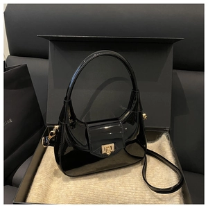Detail of black patent leather dumpling bag with gold buckle and smooth glossy finish
