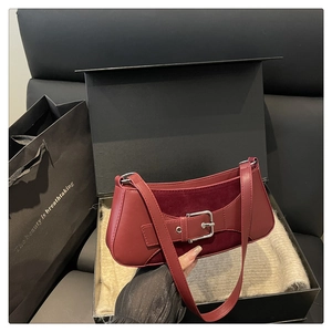 Close-up of red baguette bag with silver buckle on a gift box background