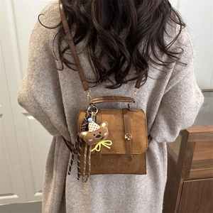 Brown frosted leather crossbody bag with teddy bear pendant shown on model's back