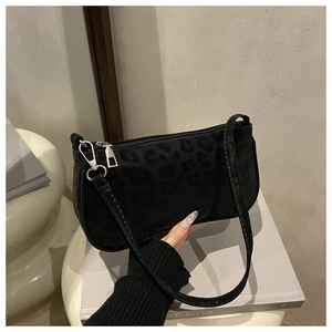 Detail einer schwarzen Baguette-Tasche mit Leopardenmuster, Silber-Reißverschluss und Satin