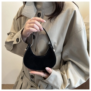 Detail of a black crescent mini handbag with premium matte texture and leather handle