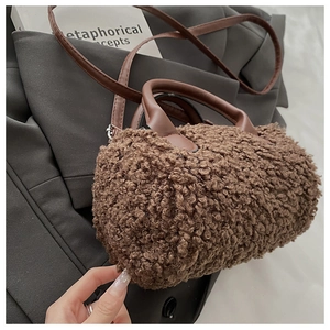 Dettaglio borsa Boston in peluche marrone con manici in pelle su uno sfondo grigio