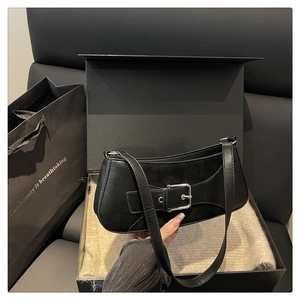 Close-up of black leather underarm bag with silver buckle in a gift box packaging