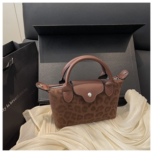 Close-up of leopard print suede handbag with leather flap and snap on soft fabric