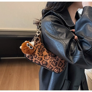 Dettaglio della borsa leopardata con tracolla a catena dorata e ciondolo mostro peluche