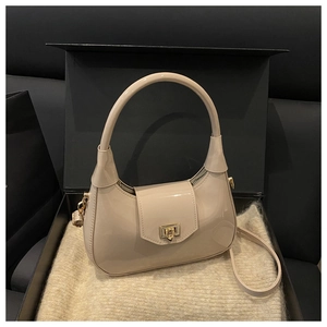 Detail of a light beige patent leather moon bag with golden square buckle in a gift box