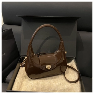 Detailed view of coffee glossy patent leather bag with gold buckle in gift box