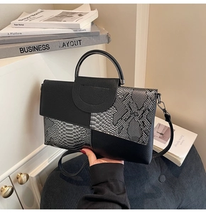 Detailed view of women's black and snake print shoulder bag with textured leather