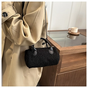 Dettaglio della borsa a cilindro nera in peluche con texture soffice e manici in pelle