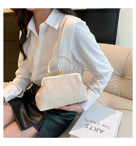 Detail of straw woven handbag with gold metal clasp and handle shown on a sofa