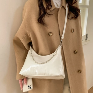 White glossy PU leather hobo bag with silver chain strap for women shown on a model