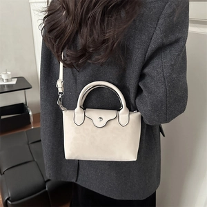 Chic cream white mini satchel crossbody bag styled with a grey blazer for winter 2025