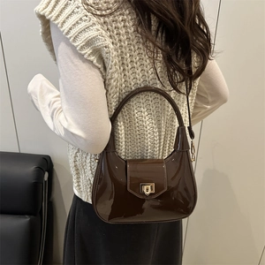 Dark brown high-gloss leather crossbody bag with top handle and gold twist lock clasp