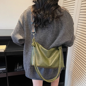Sac hobo en cuir vert olive avec large bandoulière géométrique porté par un mannequin