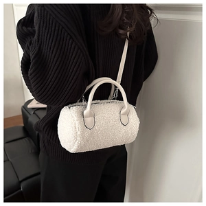 Dettaglio borsa bowling in pile bianco con tracolla in pelle beige su maglione nero