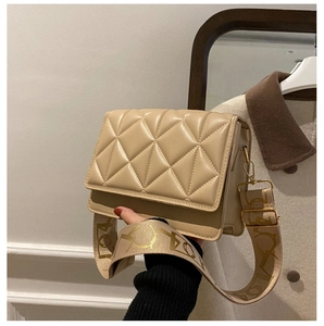 Detail of beige quilted crossbody bag featuring a wide patterned strap and matte finish