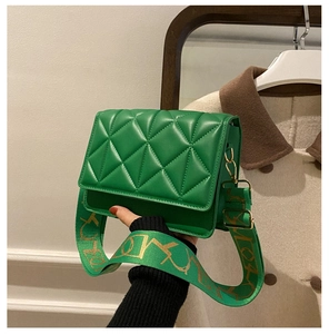 Detail of green quilted crossbody bag with stylish wide patterned fabric shoulder strap