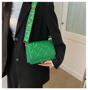 Detail of green quilted crossbody bag with embroidered wide strap on a model