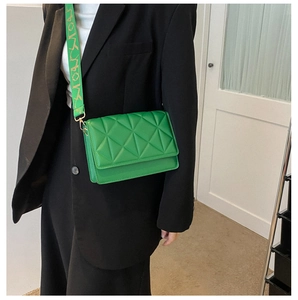 Close-up of vibrant green quilted crossbody bag with stylish wide branded shoulder strap