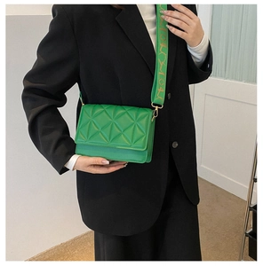 Detail of bright green quilted crossbody bag with textured geometric pattern and wide strap
