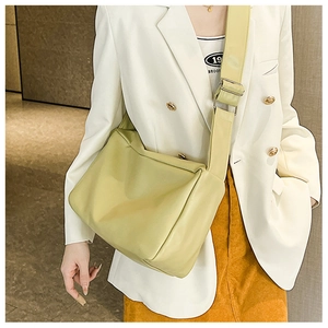 Dettaglio di una borsa tote grande in pelle verde chiaro indossata con un blazer bianco