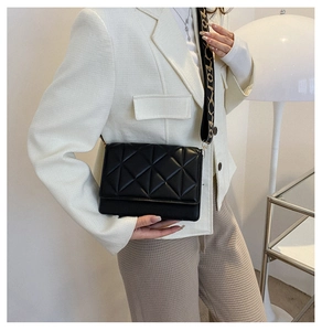 Detailed view of black quilted crossbody bag with stylish patterned wide shoulder strap