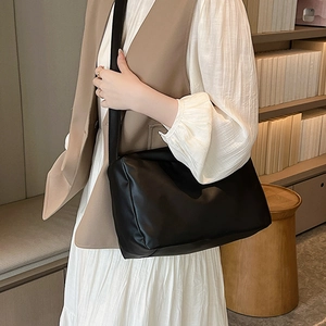 Borsa tote minimalista in pelle PU nera con tracolla larga indossata da una modella in casa