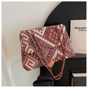 Detail of ethnic woven shoulder bag with geometric patterns and red leather chain strap