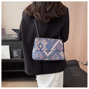 Detailed view of geometric pattern shoulder bag with gold chain strap on a model