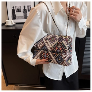 Detail of woven jacquard shoulder bag featuring geometric patterns and gold chain strap