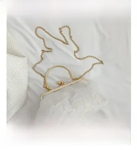 Detail of white chiffon ruched clutch with vintage gold metal frame and ball clasp closure