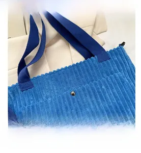 Dettaglio borsa tote in velluto a coste blu reale con fibbia magnetica e tracolla tessuta