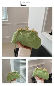Detail of green pleated dumpling bag featuring a gold metal clasp and chain strap