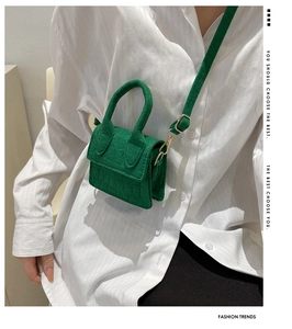 Detail van groene mini crossbodytas met krokodillenpatroon en gouden metalen haken