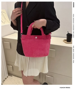Detalle de bolso saco de punto rosa fucsia con botón blanco y correa de hombro tejida