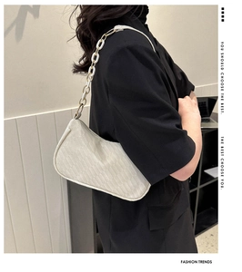 Detailed view of women's woven shoulder bag with white acrylic and gold metal chain link