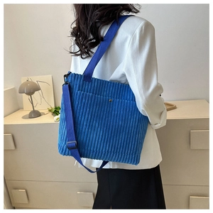 Dettaglio della borsa tote in velluto a coste blu con tasca frontale e tracolla regolabile