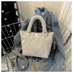 Primer plano del bolso tote de pana beige con textura rugosa y botón de metal plata