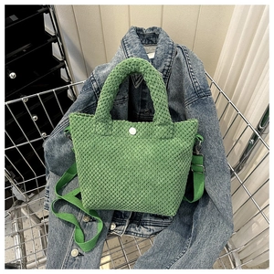 Primer plano del bolso saco verde de punto tipo gofre con textura y detalle de botón